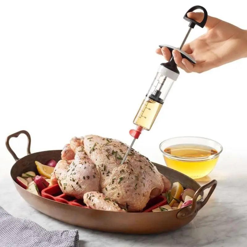 Injecteur de saveur OXO en plastique et acier inoxydable injectant marinade dans un poulet entier dans un plat de cuisson.